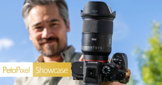 A man holds a Sony camera with a large 24mm lens towards the viewer, smiling outdoors against a blue sky. The Petapixel Showcase logo appears in the bottom left corner.