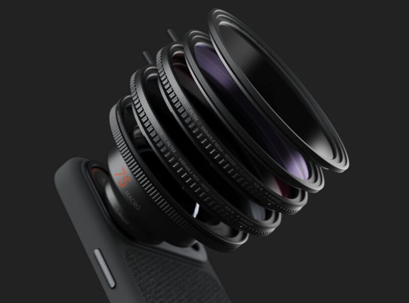 A smartphone camera with multiple lens elements and rings exploded outward, showing the internal layers of the lens assembly, set against a dark background.