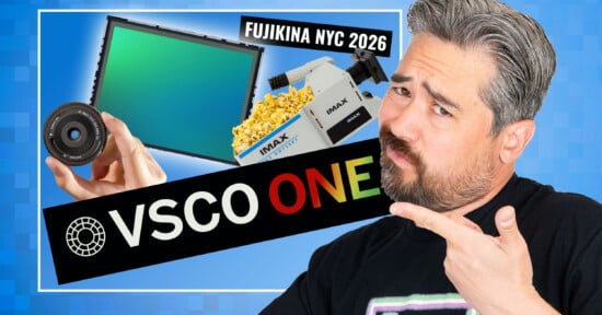 A man with gray hair and beard points to graphics of a camera lens, a sensor, popcorn, and an IMAX camera. Texts read "FUJIKINA NYC 2026" and "VSCO ONE" on a blue background.
