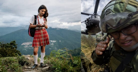 A schoolgirl in a red plaid uniform stands on a mountain path looking at her phone, while on the right, a soldier crouches with a helicopter landing behind him.