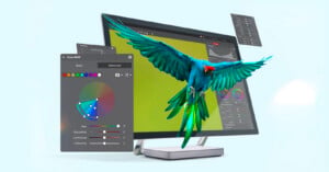 A blue and green parrot flies in front of a computer monitor displaying a bright green screen, with colorful graphic design tool windows floating around it.