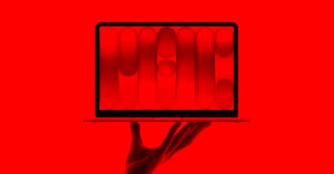 A hand holds up an open laptop. The laptop screen displays abstract red and black geometric shapes. The entire image is tinted in a bold red hue.