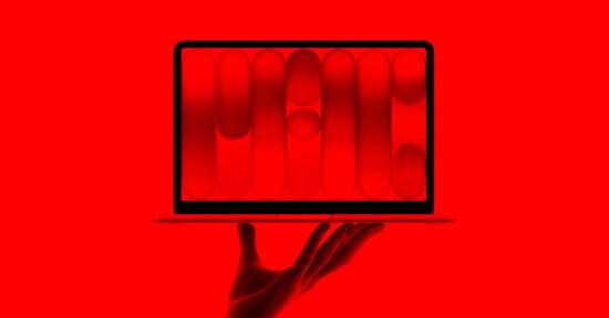 A hand holds up an open laptop. The laptop screen displays abstract red and black geometric shapes. The entire image is tinted in a bold red hue.