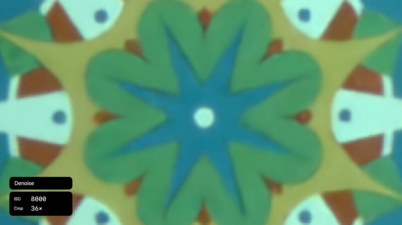 A blurry, colorful kaleidoscope pattern with blue, green, yellow, and red shapes forms a symmetrical design. In the lower left corner, a black overlay displays text: "Denoise," "ISO 8000," and "Crop 36x.