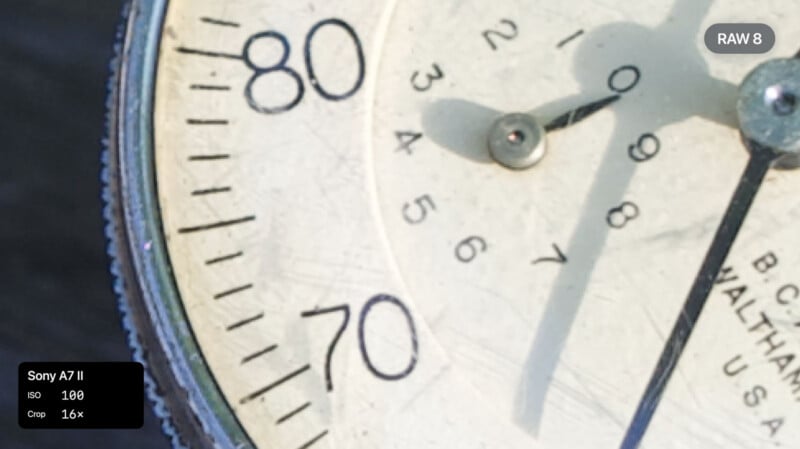 Close-up of an analog gauge with visible numbers 70, 80, and 90, and a needle pointing to around 93. Overlay text shows camera settings: Sony A7 II, ISO 100, Crop 1.6x, and the label "RAW 8.