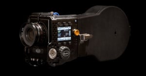 A high-end digital cinema camera with a large lens, control dials, and a display screen showing settings, set against a black background.