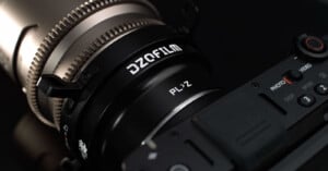 Close-up of a camera with a DZOFilm PL-Z lens adapter attached, showing detailed markings and part of the camera body in a dark setting.