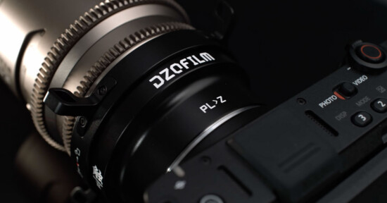 Close-up of a camera with a DZOFilm PL-Z lens adapter attached, showing detailed markings and part of the camera body in a dark setting.