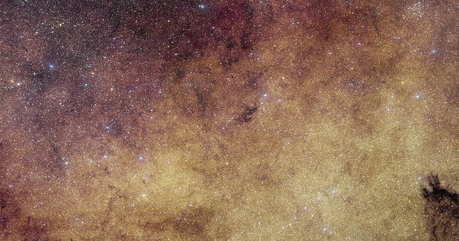 A dense field of stars and cosmic dust fills the image, creating a golden and reddish nebula-like effect, with bright and faint stars scattered throughout the scene.