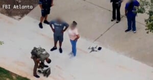 A law enforcement officer kneels near a drone and gear on a sidewalk, while two people with blurred faces stand nearby. Three others, also with blurred faces, are standing close. The text "FBI Atlanta" is on the image.