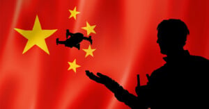 Silhouette of a person controlling a drone against the backdrop of China's national flag with large yellow stars on a red background.