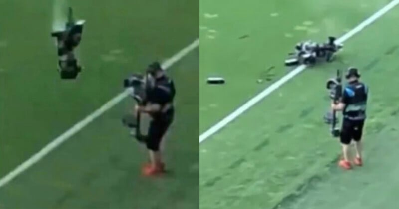 A camera operator stands on a football field as a large camera drone crashes to the ground nearby, breaking into pieces. The operator is holding a camera and wearing athletic gear.