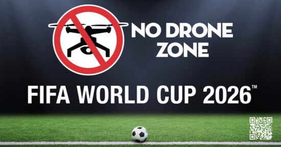 A "No Drone Zone" sign with a crossed-out drone, text stating "FIFA World Cup 2026," and a soccer ball on a field, with a QR code in the bottom right corner.