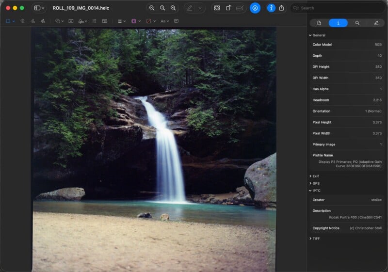 A small waterfall flows over rocks into a clear pool, surrounded by dense green trees and a sandy shore, viewed on a computer screen with image file details visible on the right side.