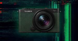 A Lumix digital camera with a large lens is centered against a dark, glitchy green and red digital background. The camera body is textured and appears in dark green and black tones.