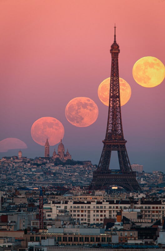 A composite image of Paris at sunset shows the Eiffel Tower and Sacré-Cœur with multiple phases of a large, orange full moon rising above the city’s skyline against a pink sky.