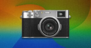A silver and black Fujifilm camera is centered against a colorful, textured background featuring gradients of orange, green, and blue.