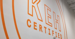 A large orange logo reading "KEH CERTIFIED" is painted on a white wall, framed by two concentric orange circles.