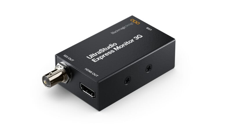 A compact rectangular device labeled "UltraStudio Express Monitor 3G" with SDI OUT and HDMI OUT ports. The device is black with white text and has a small orange logo on the top.