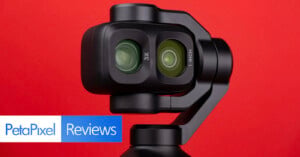 A close-up of a dual-lens gimbal camera against a solid red background, with the text "PetaPixel Reviews" in the corner.
