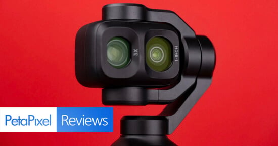A close-up of a dual-lens gimbal camera against a solid red background, with the text "PetaPixel Reviews" in the corner.