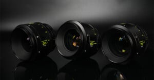 Three camera lenses labeled 35mm, 50mm, and 85mm are arranged side by side on a reflective black surface with a dark, softly lit background.
