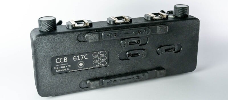 A black, rectangular panoramic film camera with three cold shoe mounts on top and a label detailing exposure settings for 6x9, 6x12, and 6x17 formats.