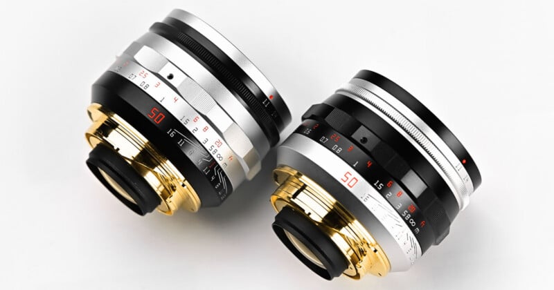 Two camera lenses with metallic finishes—one silver and gold, the other black and gold—are placed side by side on a white surface. Both feature red, white, and black markings and numbers.