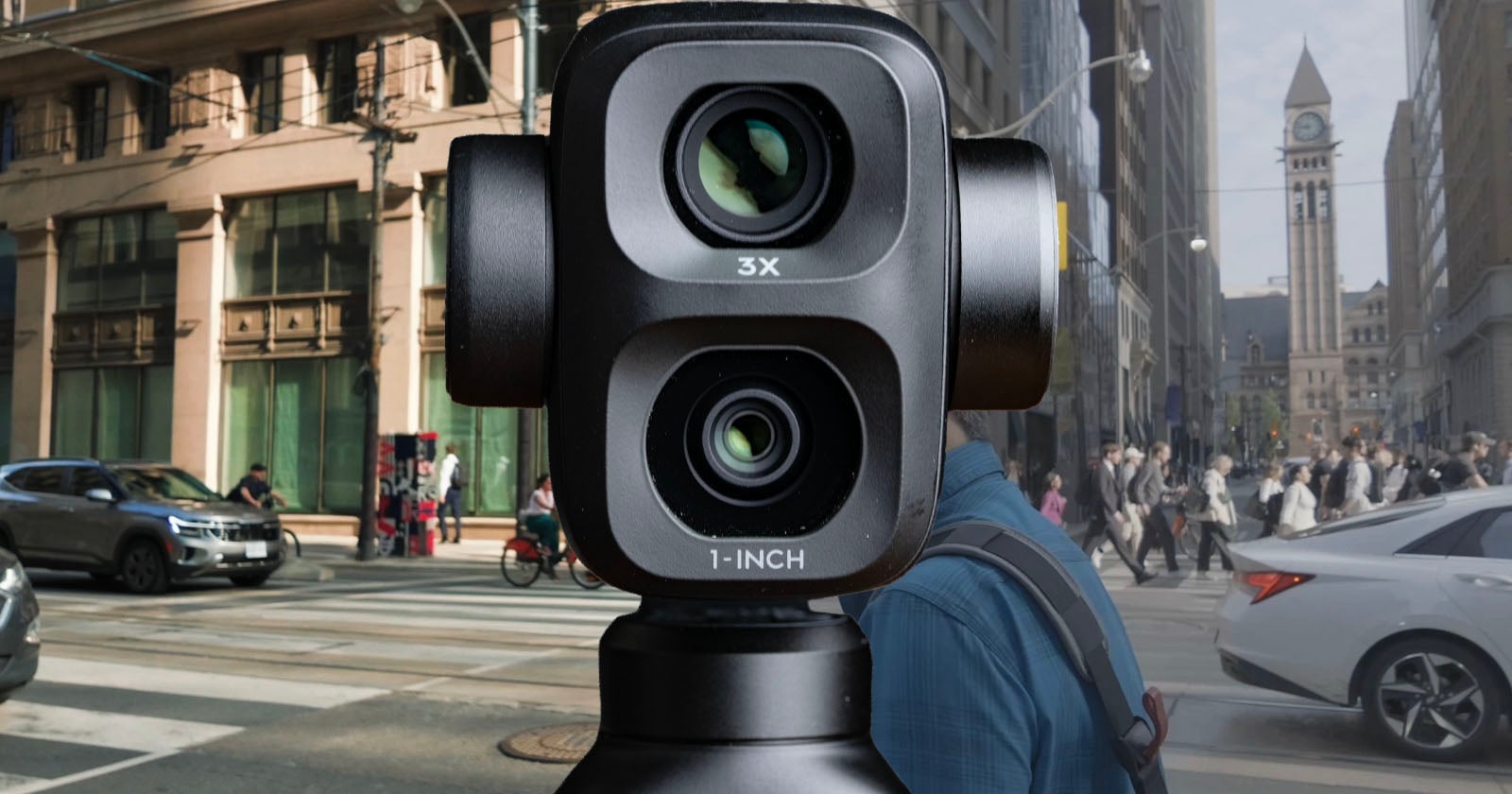 A close-up of a dual-lens camera labeled "3X" and "1-INCH" set against a busy city street with cars, pedestrians, and tall buildings in the background.