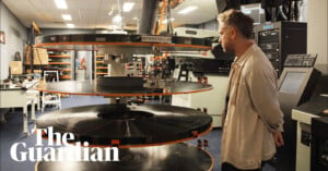 A person stands beside a large film reel labeled "Interstellar" in a projection room filled with equipment. The Guardian logo is visible in the bottom left corner.