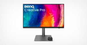 A BenQ Creative Pro monitor displays a vibrant, abstract multicolored design on the screen. The monitor is mounted on a sleek, minimalist stand with a circular control dial at the base.