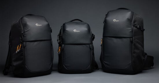 Three black Lowepro backpacks of varying sizes stand side-by-side against a plain gray background.