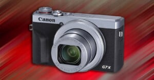 Canon G7 X digital camera with extended lens, set against a vibrant red and orange streaked background.