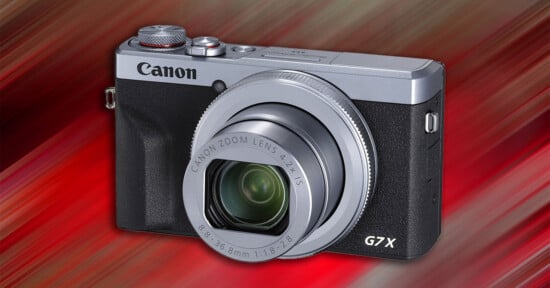 Canon G7 X digital camera with extended lens, set against a vibrant red and orange streaked background.