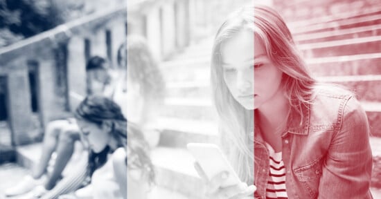 A young woman sits on outdoor steps looking at her phone, with a faded French flag overlay on the image. Other people are seated in the background, blurred and engaged with their own devices.