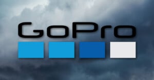 The GoPro logo with four squares in light blue, blue, dark blue, and gray on a cloudy sky background.