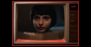 A close-up of a young person with short dark hair appears on an old-fashioned television screen, which displays the channel as UHS. The TV has wood paneling and red lighting around the edges.