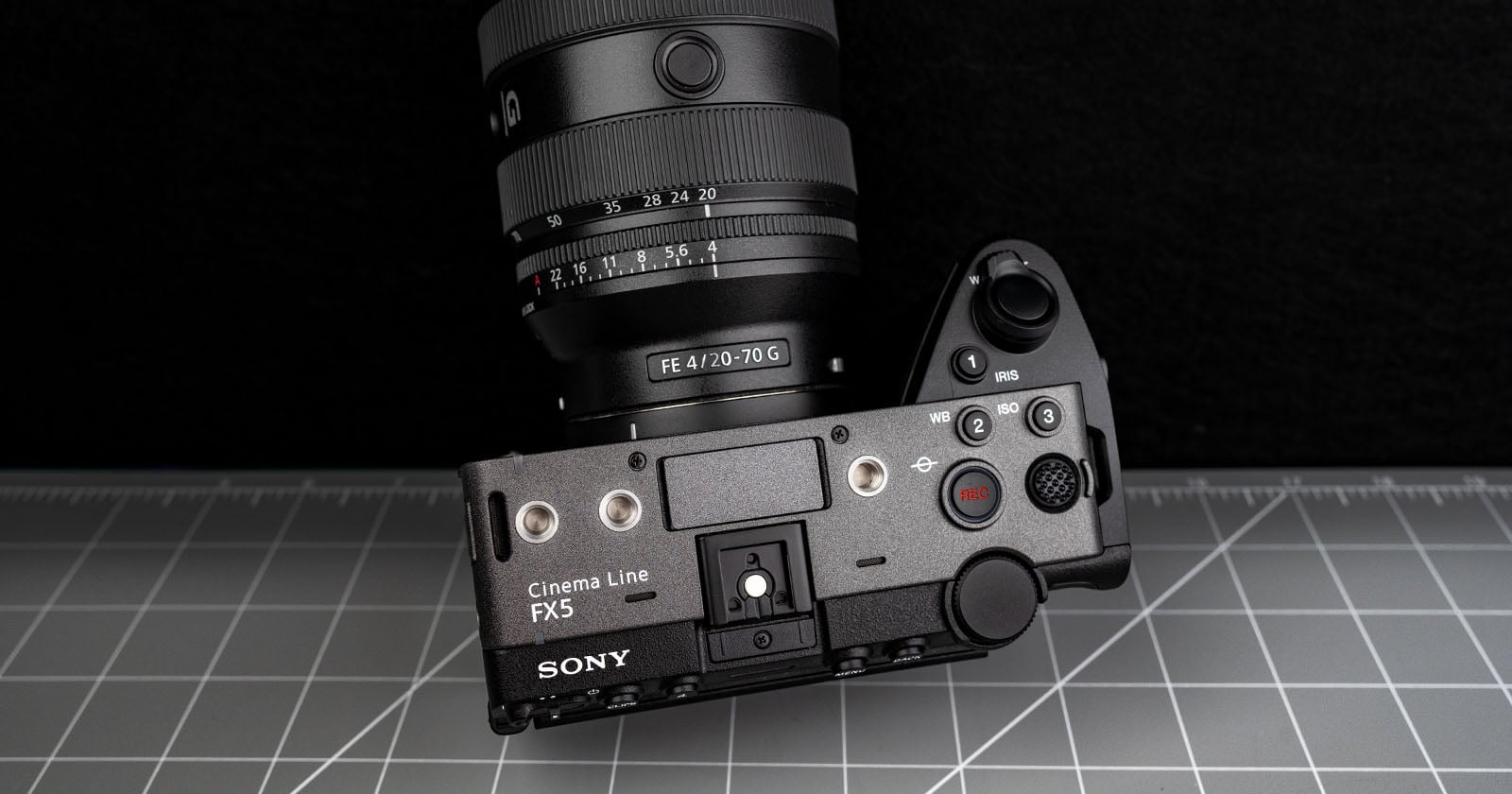 A Sony Cinema Line FX5 camera with an attached FE 4/20-70 G lens is positioned on a gray grid-pattern surface, viewed from above with controls and buttons visible.