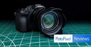 A Sony camera with a large lens sits on a green cutting mat. The Petapixel Reviews logo is displayed in the lower right corner.