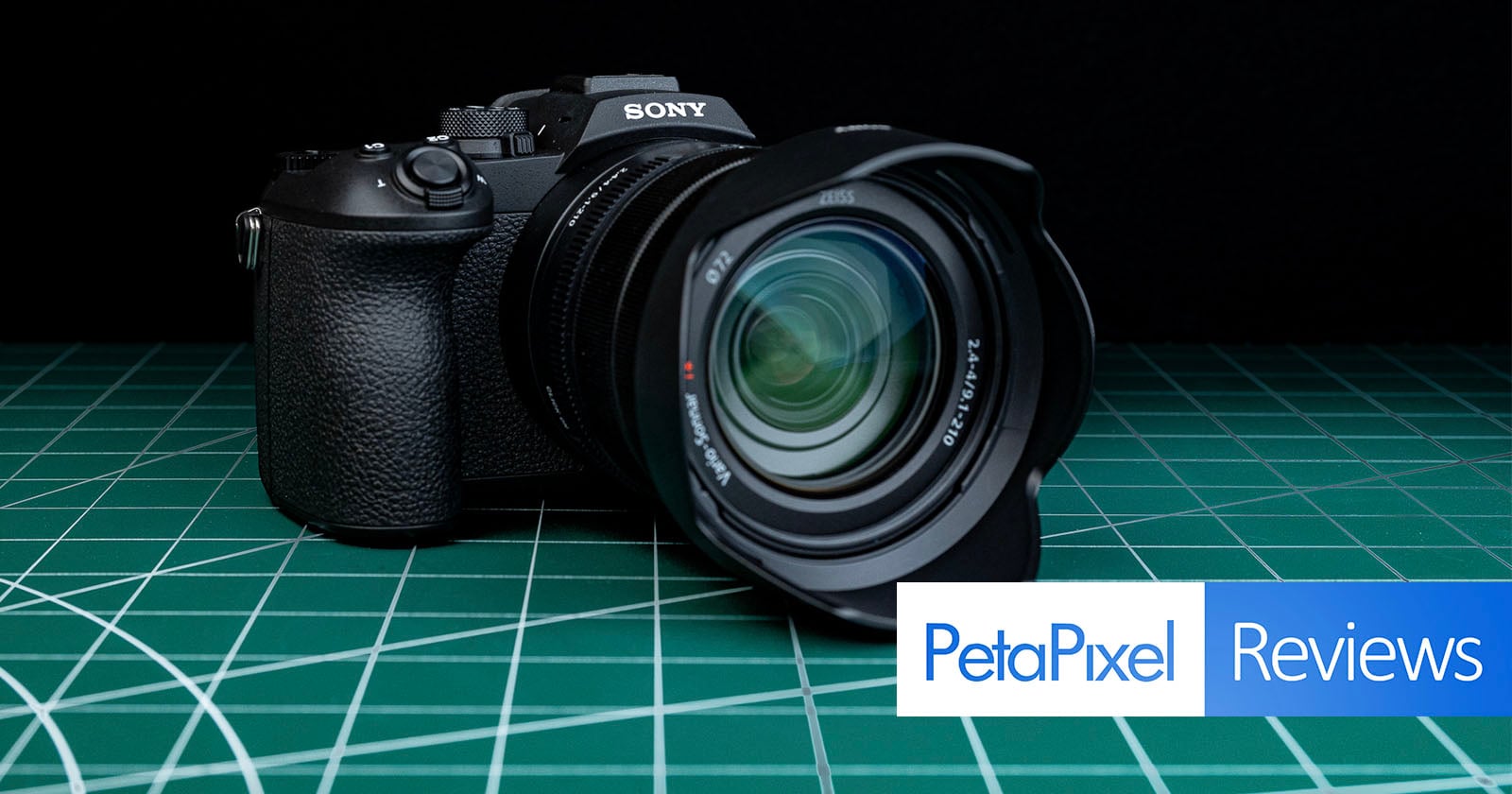 A Sony camera with a large lens sits on a green cutting mat. The Petapixel Reviews logo is displayed in the lower right corner.
