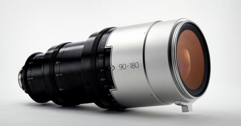 A professional camera lens with a metallic silver finish and black focus rings, marked "90-180," displayed against a plain white background.