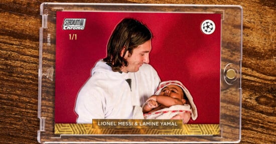 A trading card in a clear case shows a man in white holding a baby in pink, both against a red background. The card reads “LIONEL MESSI & LAMINE YAMAL” at the bottom. Top left text: “STADIUM Chrome 1/1.”.