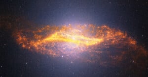 A bright, glowing spiral galaxy with fiery orange and yellow dust swirling around its center, set against a dark, star-filled space background.