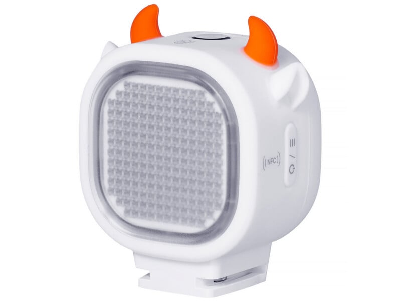 A white, square-shaped portable LED light with orange devil horns on top, featuring a grid-patterned light panel and side buttons labeled with NFC and power icons.