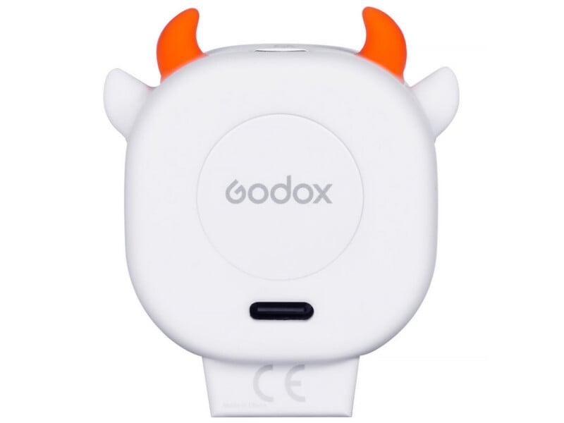 A white, rounded electronic device with orange devil horns and small side ears, featuring a central Godox logo, a USB-C port, and a CE mark at the bottom.