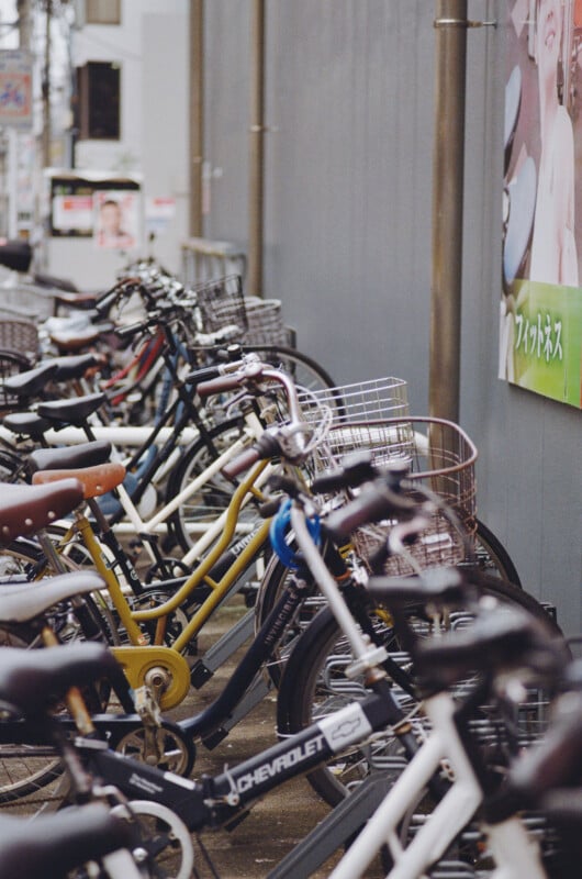 A row of bicycles parked in a line along a gray wall, with a Chevrolet-branded bike in the foreground.