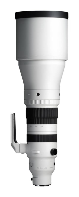 A white Sigma 300-600mm 1:4 DG telephoto camera lens stands vertically against a white background.