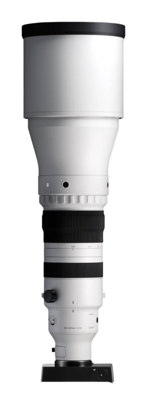 A long, white telephoto zoom lens with black grip rings and a black camera mount base, standing vertically against a white background.