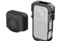 A black protective silicone lens cover sits to the left of a black camera cage housing a rectangular action camera.