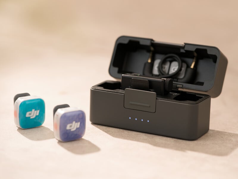 A DJI wireless microphone system featuring two small, colorful transmitters and a charging case containing a receiver and cables.